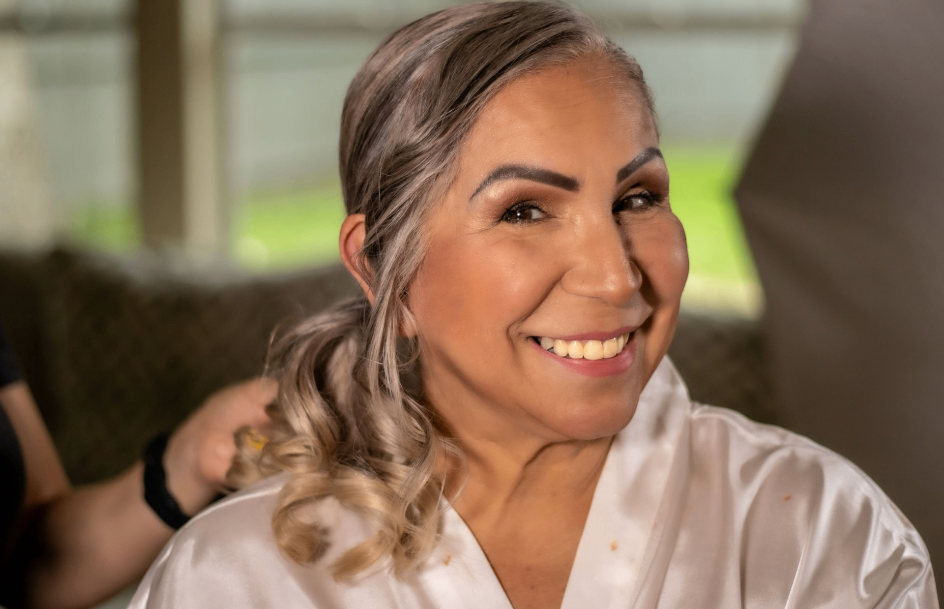Bride smiling while getting her hair styled