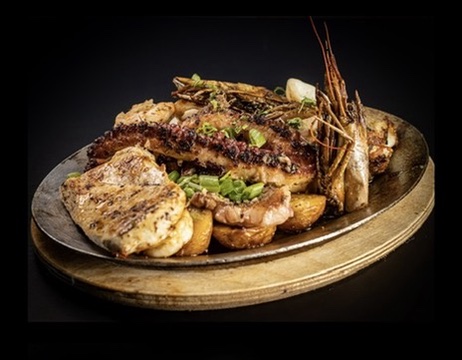 Grilled seafood and meat platter on a rustic brass tray